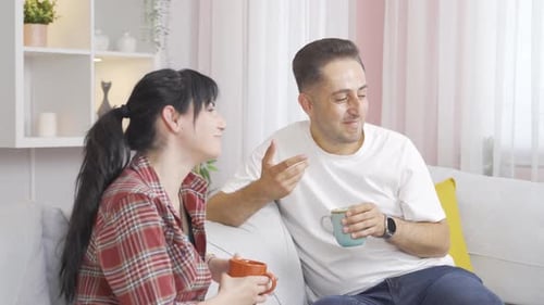 Cheerful Couple Talking and Drinking Coffee at Home