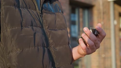 Close Up of Hand Closing Cigarette Pack in Front of Building in Sunlight