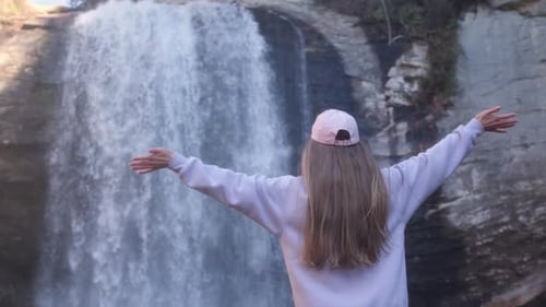 Woman enjoying the beauty of a mountain waterfall