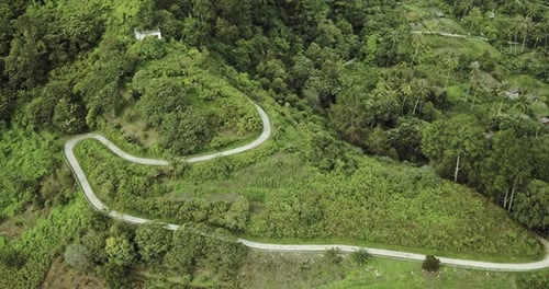 The winding road in the hills descends towards the lake.