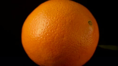 Rotating whole orange in extreme close-up highlighting peel texture and natural color.