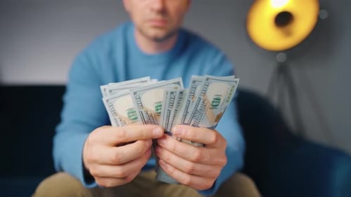 Man Counting Stacks of United States Currency Indoors