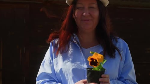 Woman Holds Pansy Flower in Rural Outdoor Setting