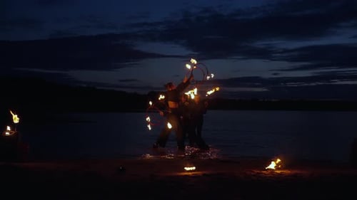 Fire Dancers Perform on Dark Sandy Beach at Night