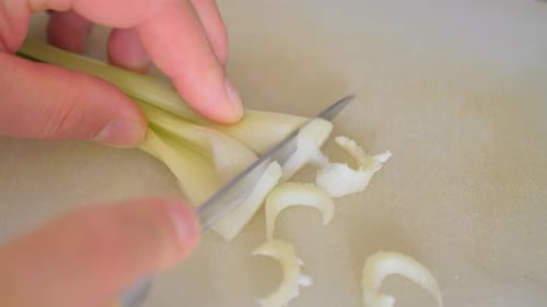 Cuts a Stalk of Celery Into Small Slices with a Kitchen Knife on a Kitchen Board for a Vegetable
