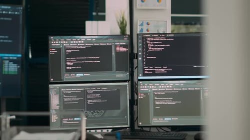 Escritorio de oficina vacío con varias pantallas que ejecutan un script de desarrollo de software