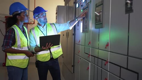 Engineers Inspecting Electrical Panels with Laptop