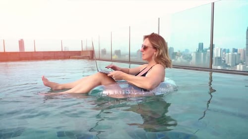 Eine junge Unternehmerin arbeitet im Sommer am Pool des Resorts an ihrem Computer.