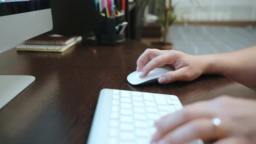 Eine Frau, die von zu Hause aus arbeitet, steuert einen Computer mit einer drahtlosen Maus