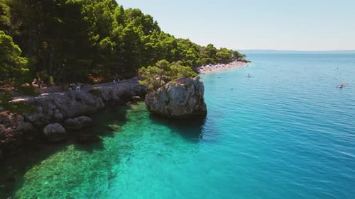Crystal-clear waters of the Adriatic Sea border the lush landscapes of Brela, Croatia. Popular touri