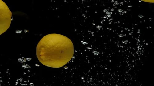Yellow Lemons Falling and Sinking in Water