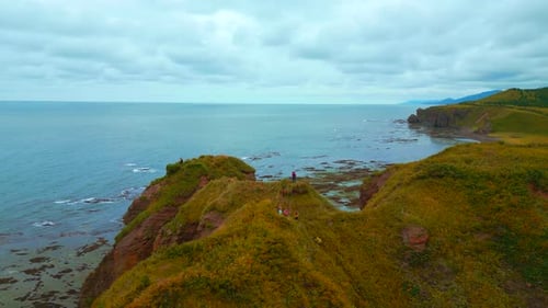 Inspiring approach to edge of rocky coast. Beautiful view of tourists on cliff overlooking sea