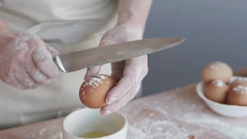 Adult Cracks Egg with Knife While Baking
