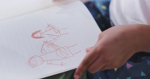 Child Draws Cartoon Figures with Pencil on Paper