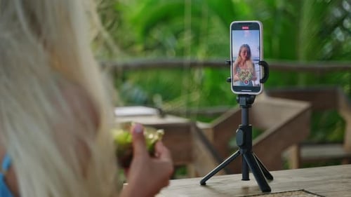Smartphone Screen with Young Woman Blogger Making Selfie Video with Green Salad in Tropical Island