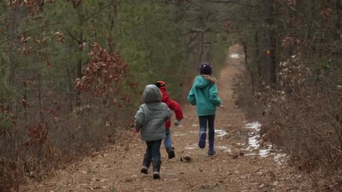 Kinder laufen im Winter einen Waldweg entlang.