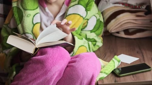 Frau liest ein Buch auf einem gemütlichen Sofa bei Tageslicht aus dem Fenster