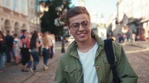 Smiling Teenager in City Street Listens to Music