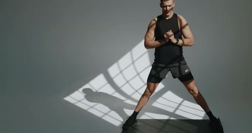 Muscular Man Stretching on Gray Mat Indoors