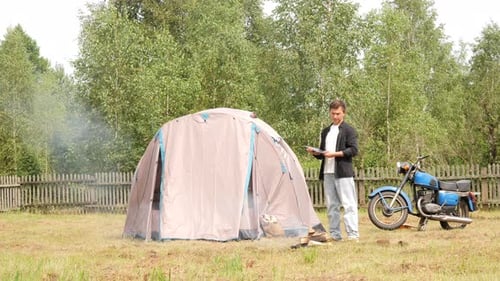 Man Camping in Rural Field with Motorcycle