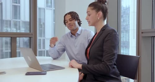 Two Young Professionals Collaborate on Laptop in Modern Office