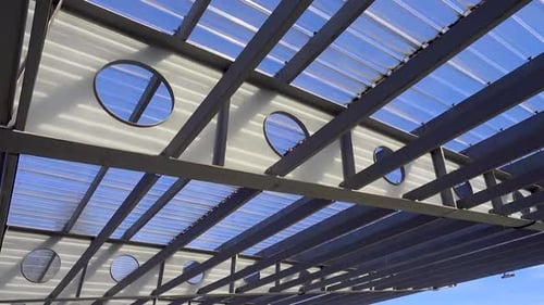 Metal structures of a sun canopy against a blue sky.