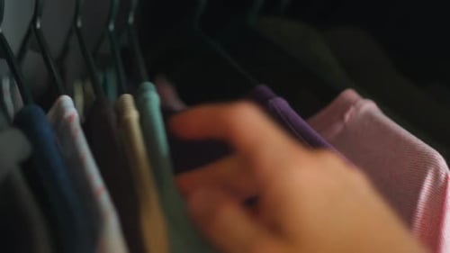 Hand Reaches into Closet of Colorful Shirts