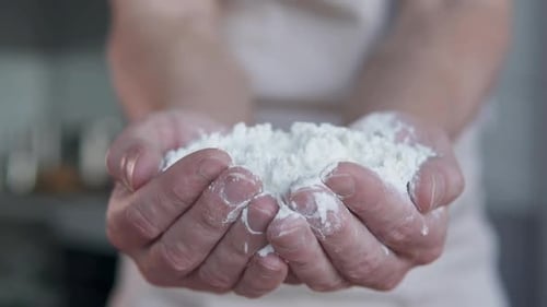 The cook holds flour in his palms. Cooking bread and pizza. Slow motion.