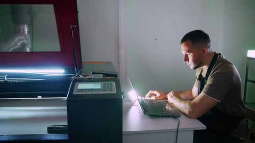 Techniker steuert Lasergravurmaschine mit Laptop