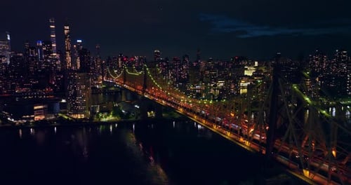Wonderful Queensboro Bridge lit in green and orange. New York scenery full of lights at night time.