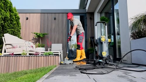 Man Cleans Patio with Pressure Washer Outside