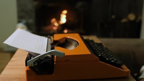Orange Typewriter on Desk with Lit Fireplace