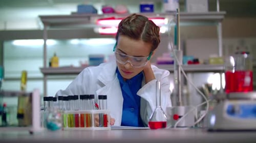 Woman Scientist Writing in Laboratory with Test Tubes