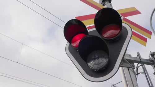Rote Warnlichter blinken am Bahnübergang. Nahaufnahme.