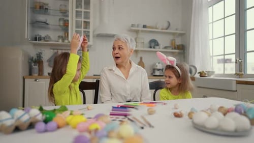 Grandmother and Granddaughters Decorating Easter Eggs Together