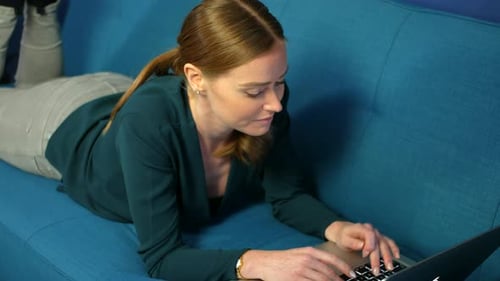Young Woman Using Laptop on Couch Indoors