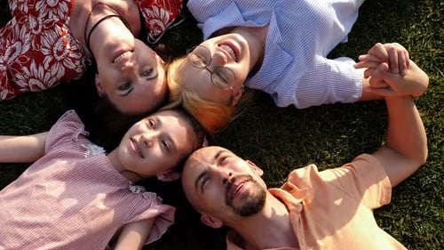 A Happy Family with Children Lying on the Grass in a Circle and Laughing