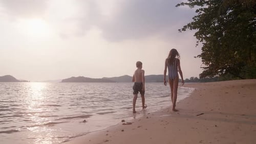 Boy And Girl Walking Along The Seashore