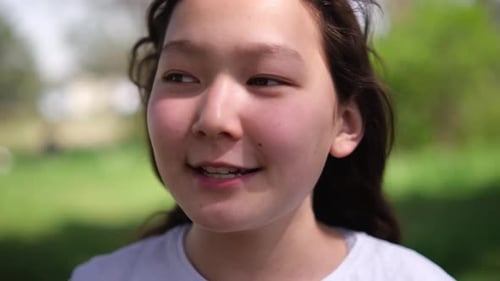 Closeup of an Asian Girl in a Light Blue Jacket and White Shirt with a Cheerful Expression The