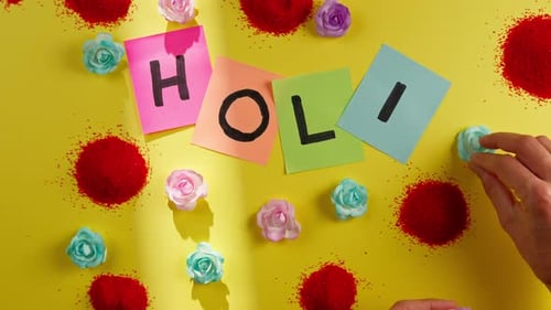 Buchstaben für das Holi Festival auf gelbem Hintergrund kleben