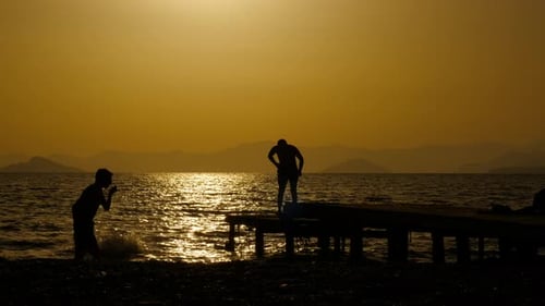 Silhouette of Joyful Boys Jump Into Dusk Sea