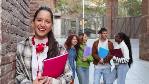 Cheerful Girl Holding Notebooks While Smiling with Friends in an Academic Setting at a University