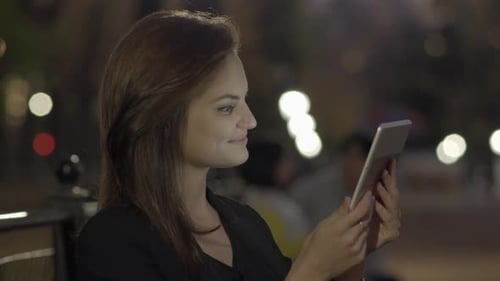 Young Woman Using Tablet Computer In The Park At Night
