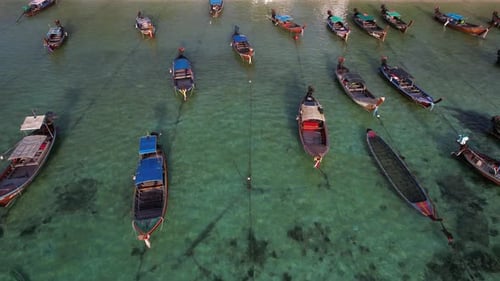 Footage of a lot of long-tailed boats float on the sea outside the white beach.
