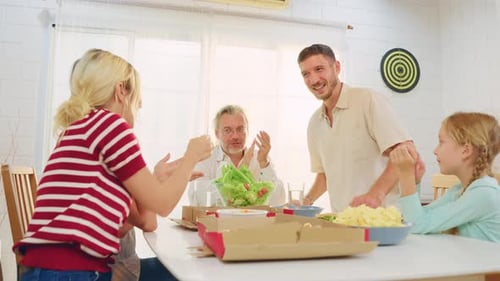 Smiling Family Clapping for Salad at Dinner Table