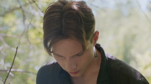 Young Man Looks Up with Serious Expression and Subtle Smile in Forest