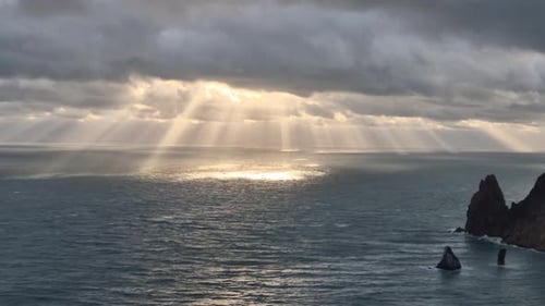 Sea Clouds Sunlight Breaking Through Dramatic Sky Over Rough Ocean with Rocky Coast