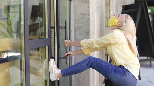 An Impatient Caucasian Woman Opens the Door of the Store with Her Foot