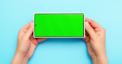 Woman's Hands Holding Smartphone with Green Screen on Blue Background