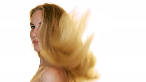 Slow motion shot of hair falling on the shoulders of a young woman in the studio on white background